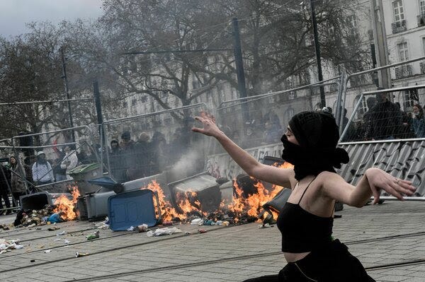  A woman wearing a black face covering poses by a burning barricade during a demonstration in Nantes on March 18.