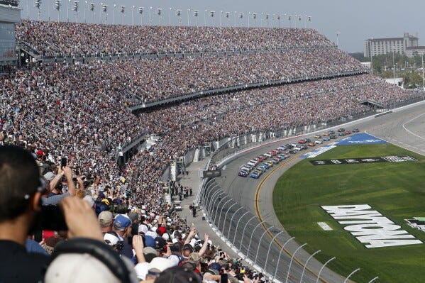 FILE - A sold out crowd watches as Alex Bowman, front left, and Kyle Larson, front right, lead the field to start the NASCAR Daytona 500 auto race at Daytona International Speedway, Sunday, Feb. 19, 2023, in Daytona Beach, Fla. A new NASCAR season begins with rivals attempting to dethrone Team Penske after two years atop the Cup Series, all while a compelling off-track battle rages on over revenue sharing that threatens to overshadow the competition. (AP Photo/David Graham, File)