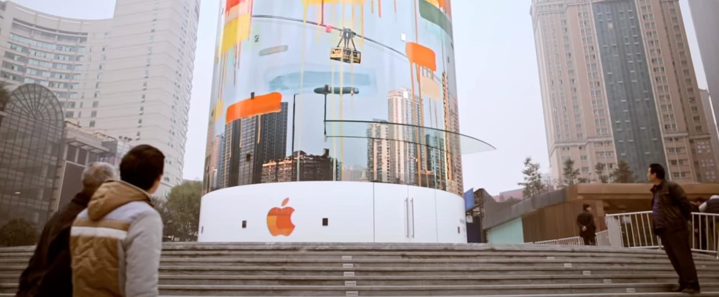 The exterior of Apple Jiefangbei wrapped in a mural. Passersby glance at the store.
