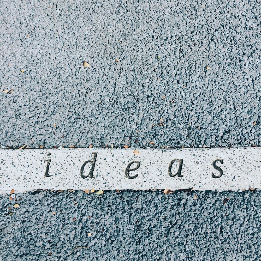 The word “ideas” written on a white strip against a blue stone background.