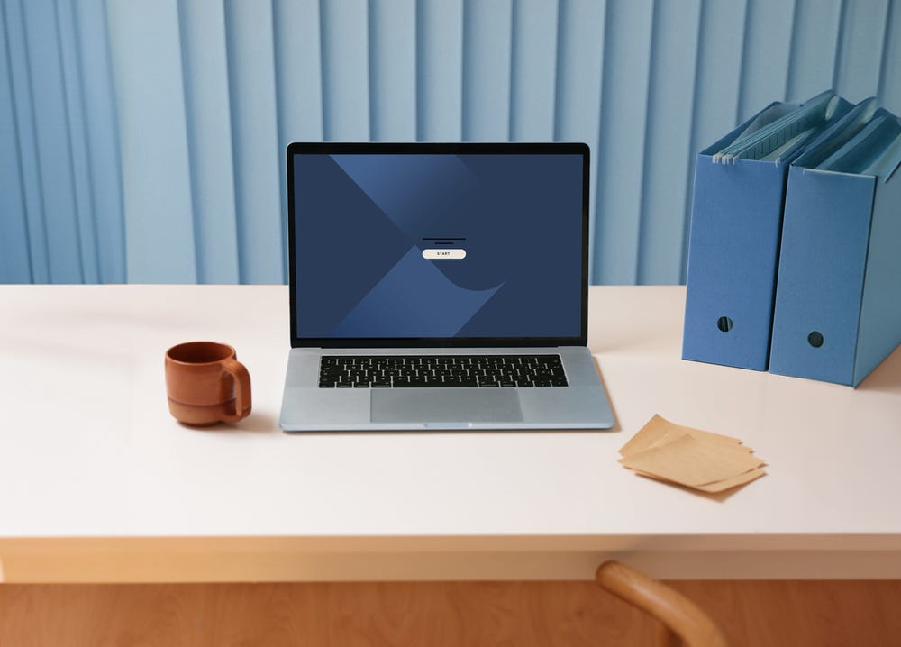 Open Laptop on desk, empty chair. coffee mug and note paper.