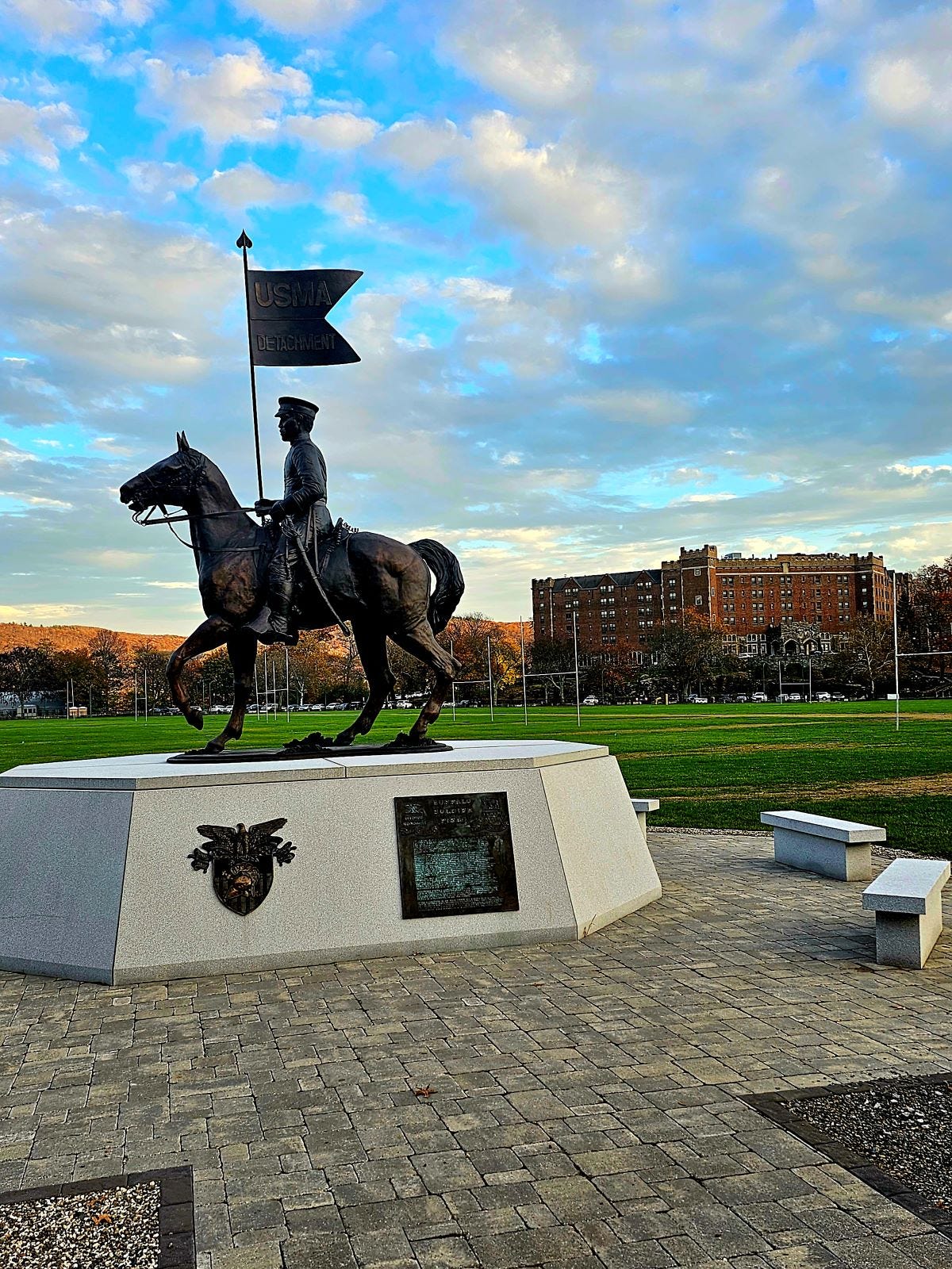 A monument honoring horse soldiers with thayer hotel in the background.
