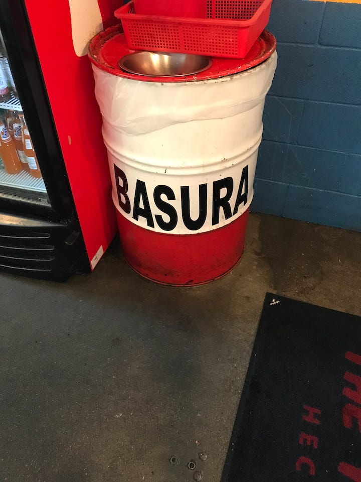garbage can in a taco stand that says BASURA on the side