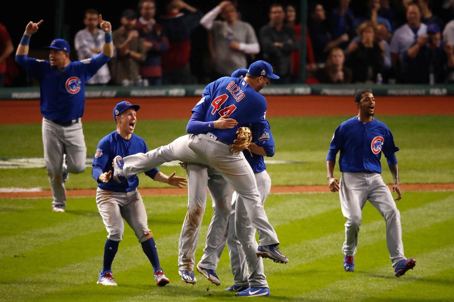 Some boys in blue uniforms are very excited on a baseball field.