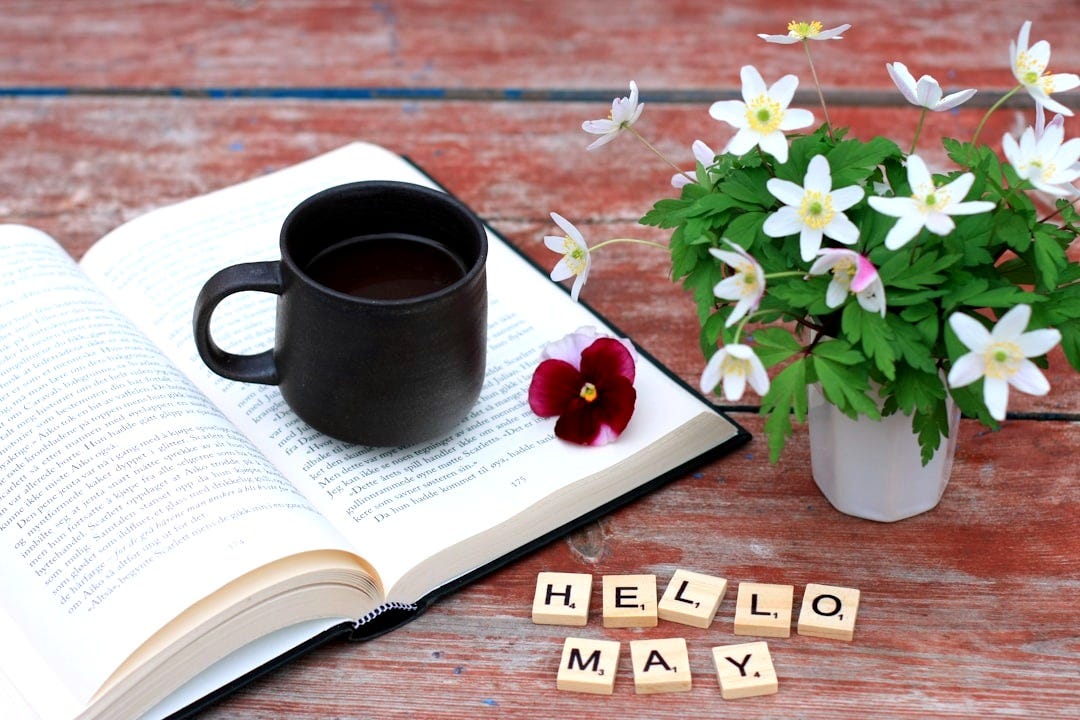 a cup of coffee next to a book and flowers a cup of coffee next to a book and flowers