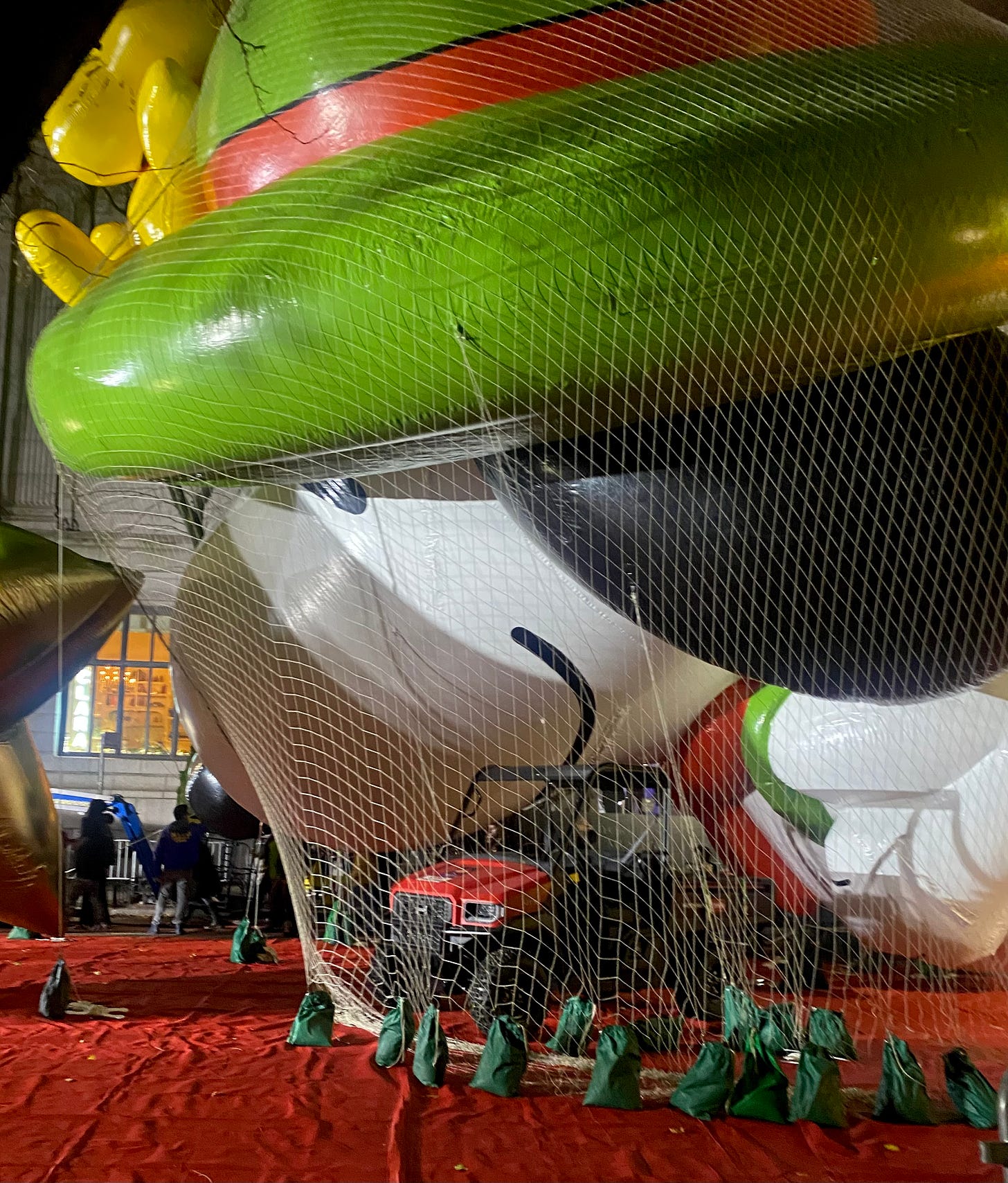 A Snoopy ballon tied down on West 76th Street for the parade. It has a green hat, on which Woodstock is perched.