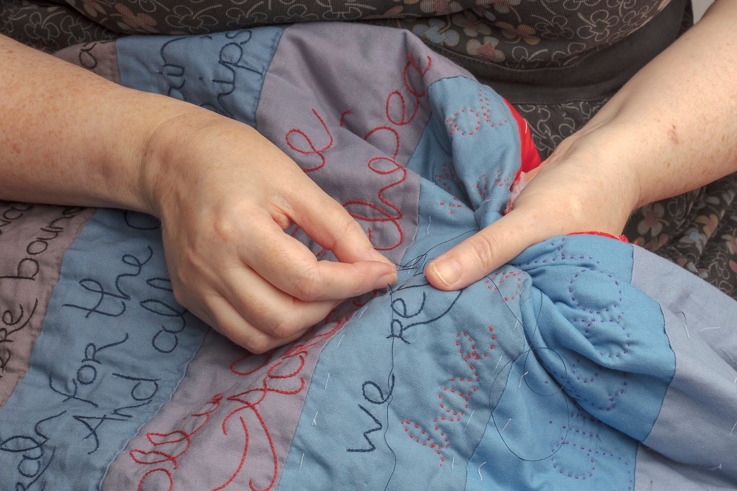 Hand stitching a quilt with needle and thread.