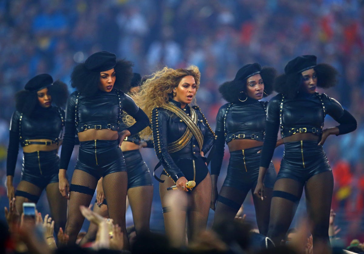 Beyonce standing with her dancers who are all wearing black berets and black body suits