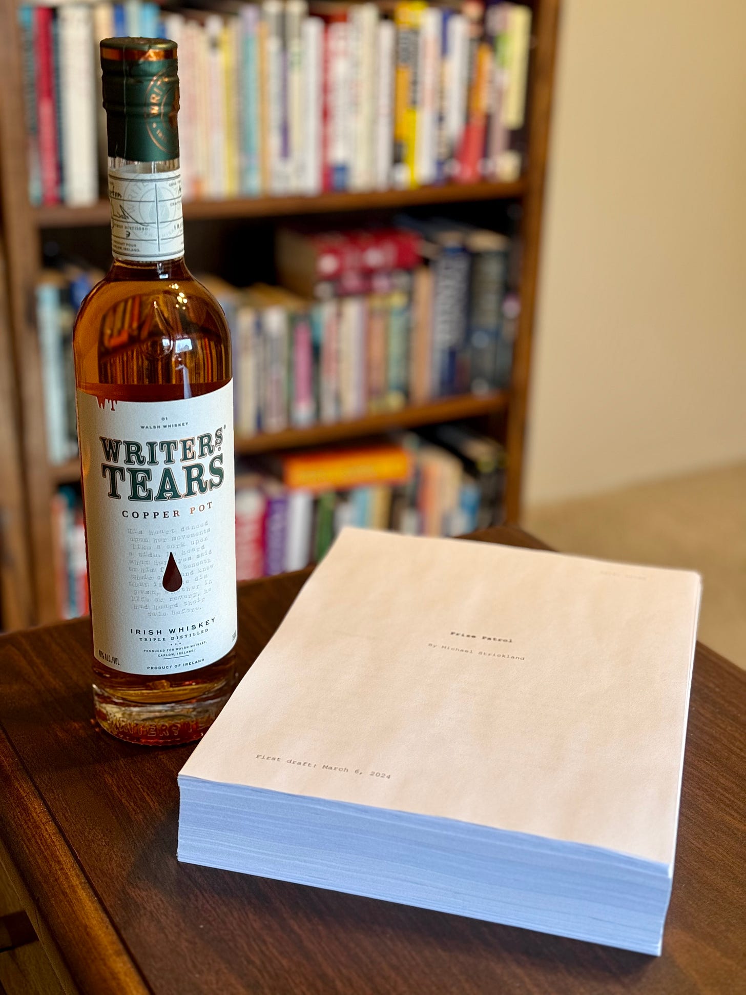 A printed manuscript sits on a desk next to a bottle of Irish whiskey named Writers' Tears