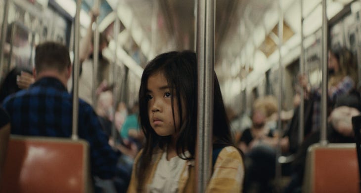 A film still showing a young girl standing on a train