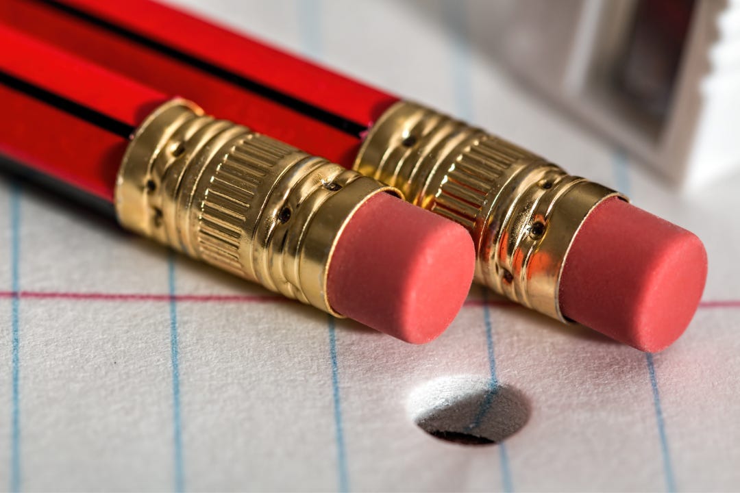 two red pencils with erasers on the ends resting on a notepad