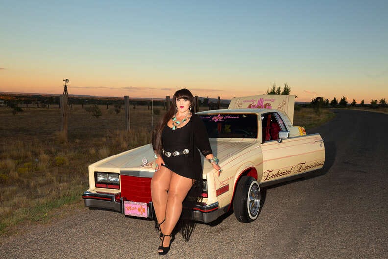 woman poses in front of her custom lowrider car