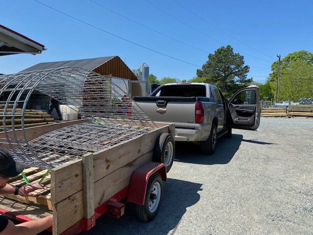 a truck and small wooden trailer stacked with cattle panels