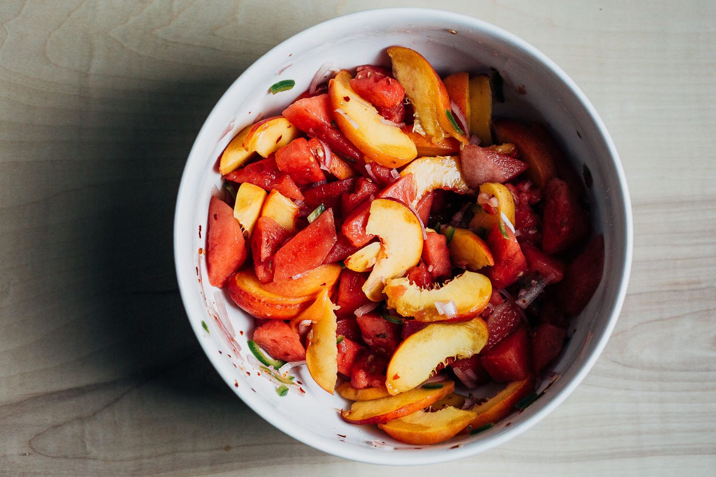 A large white bowl with a watermelon and peach salad