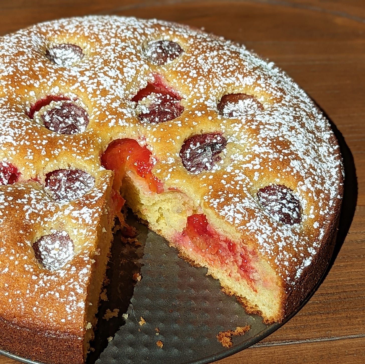 yellow round cake with a slice taken out to show red plums