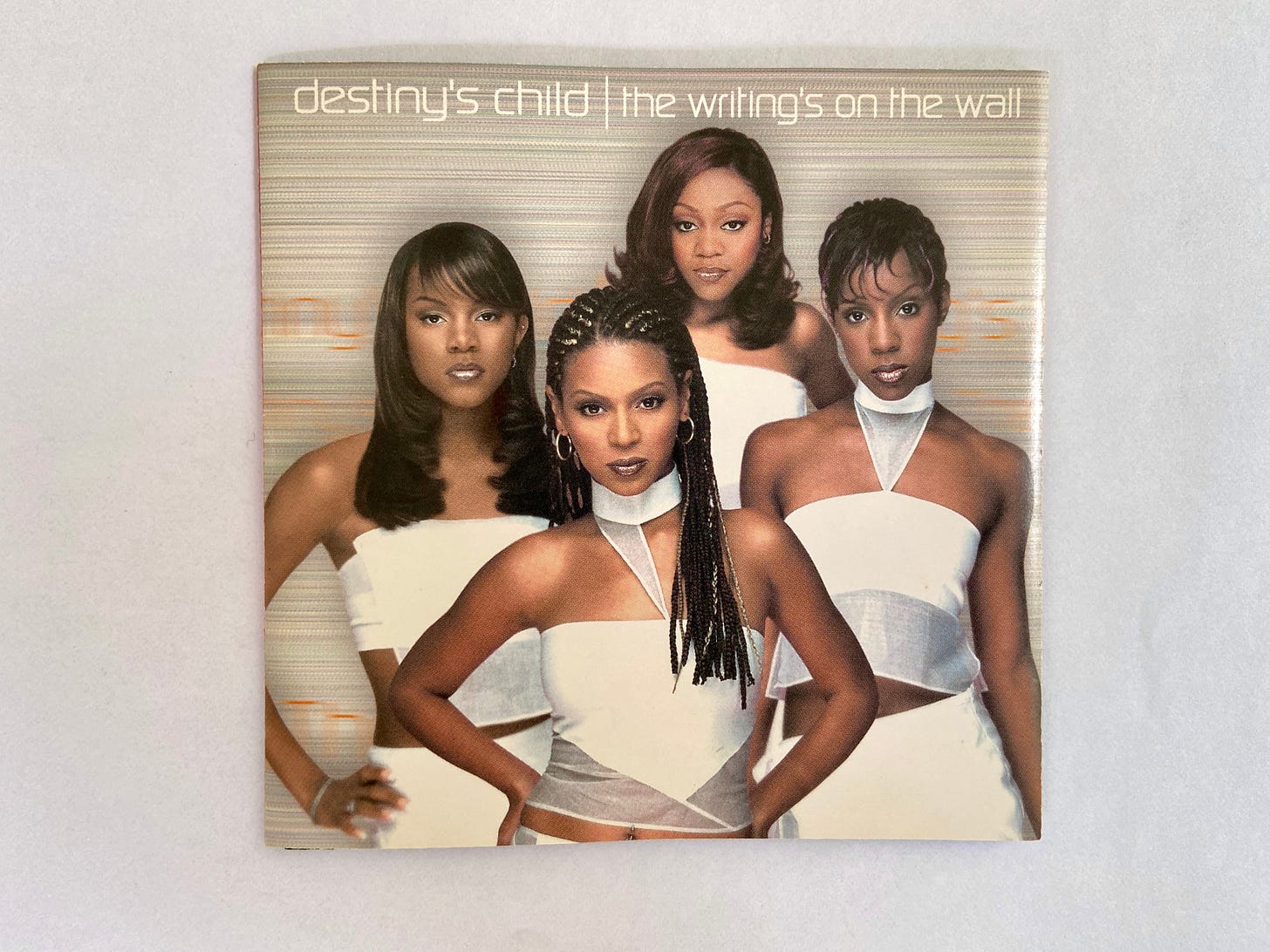 the album cover outside of its jewel case. four young Black women pose fiercely in sleek and trendy white outfits.