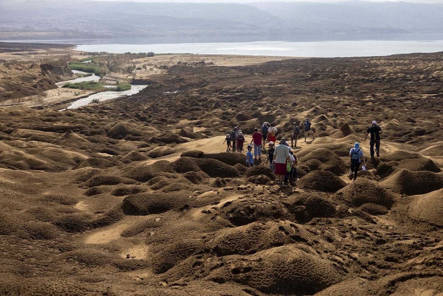 A group of Israeli hikers walk on the hills near the Jordan River where the steam pours into the Dead Sea, near the West Bank city of Jericho, on October 14, 2022. (AFP)