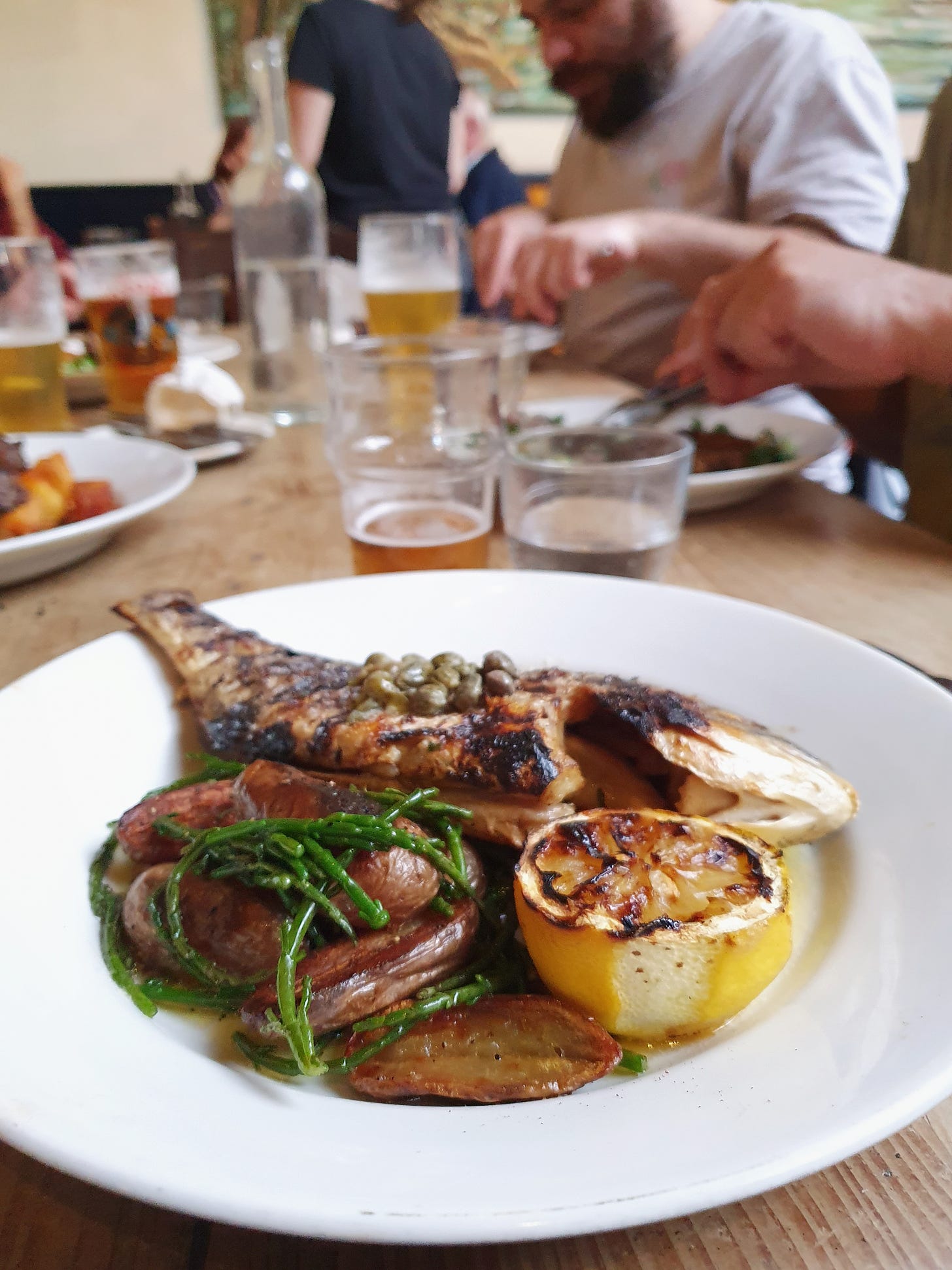 Photo of a plate of food with people eating in the background