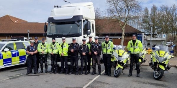 11 members of the Commercial Vehicle Unit with police cars, police motorsycles and an HGV cab