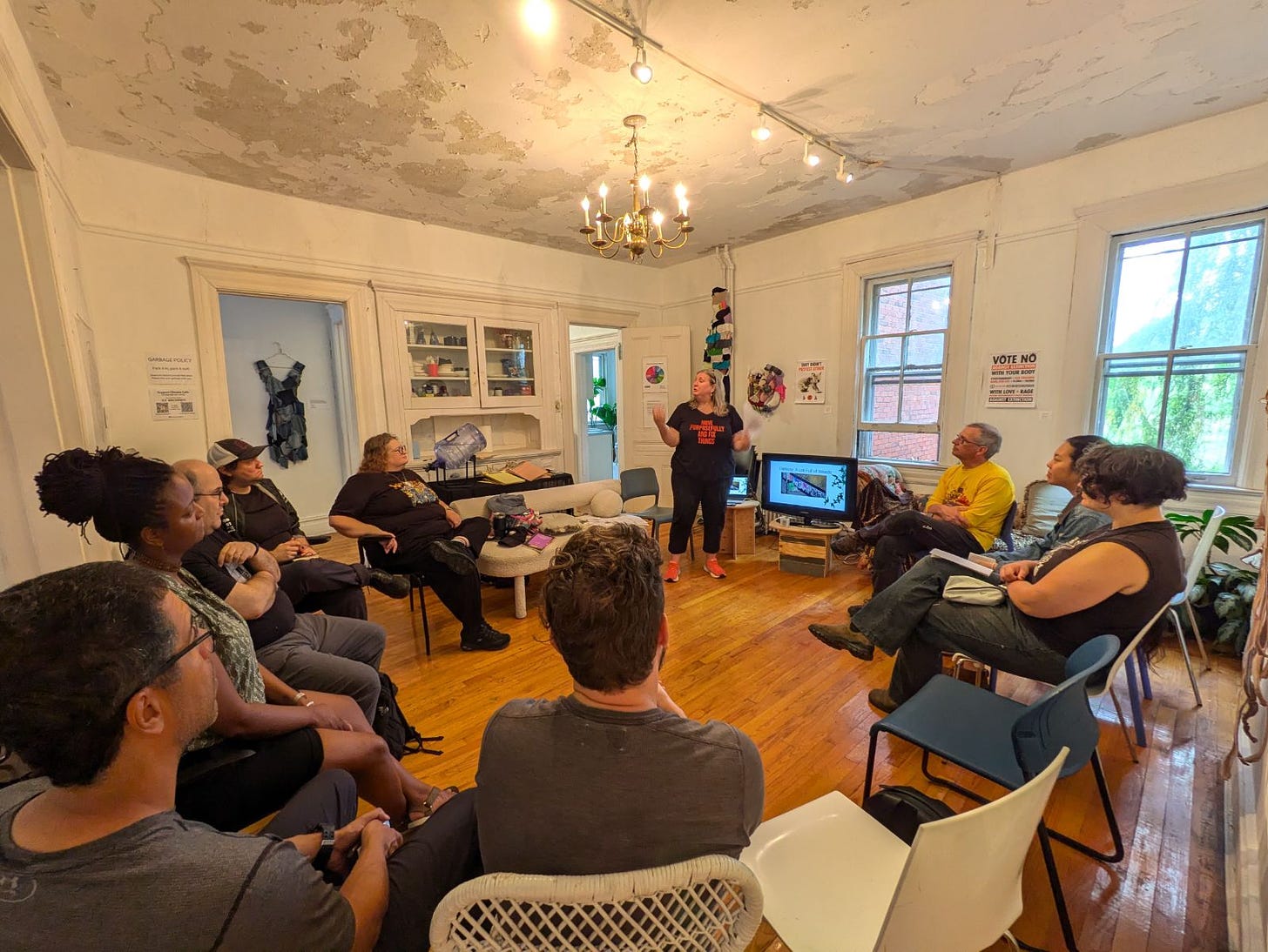 Sue standing in the living room of a house on Governor's Island that houses the Climate Imaginarium, surrounded by students, teaching solarpunk