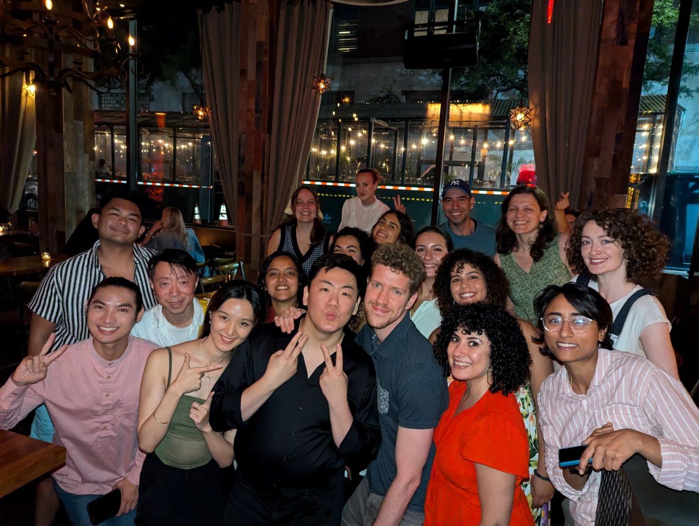 A group of people of different races and genders smile at the camera in bar at night