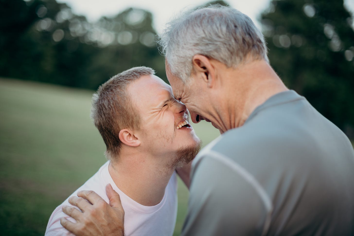 A young adult with Down Syndrome looks in the eyes of an adult friend