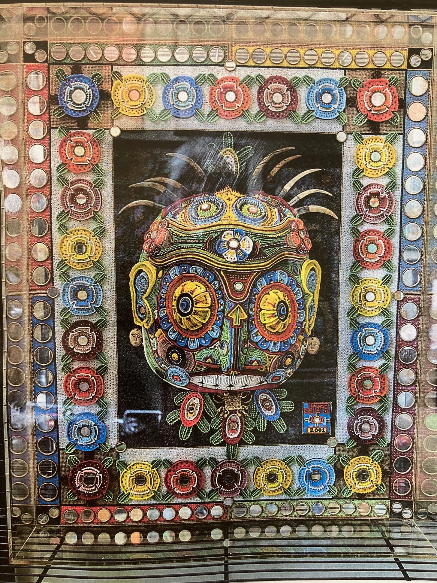 A wildly colorful artwork. At its center is the figure of a head, with all sorts of hallucinogenic elements.