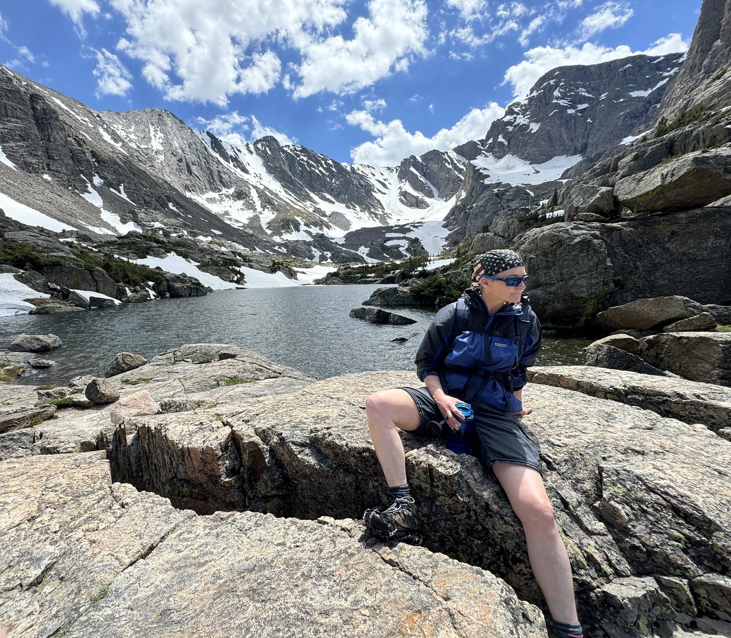 Charlie sitting on a rock on a high mountain lake shore