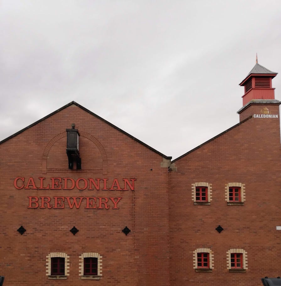 A red brick building with small, red windows. Red wording on the wall reads: CALEDONIAN BREWERY.