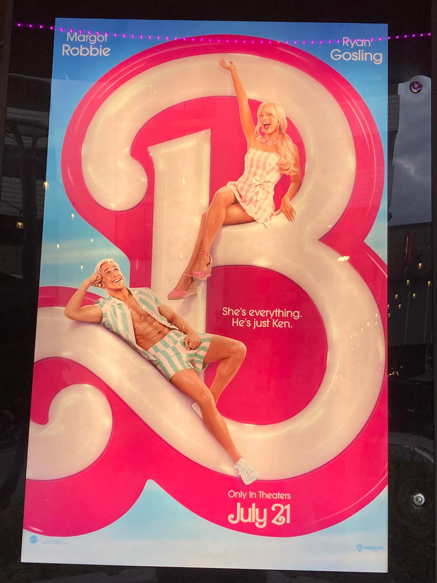 The Barbie movie poster, which has a giant B with Barbie and Ken sitting on it and the text “She’s everything. He’s just Ken.”
