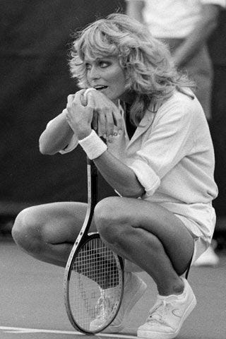 This may contain: black and white photograph of a woman holding a tennis racket