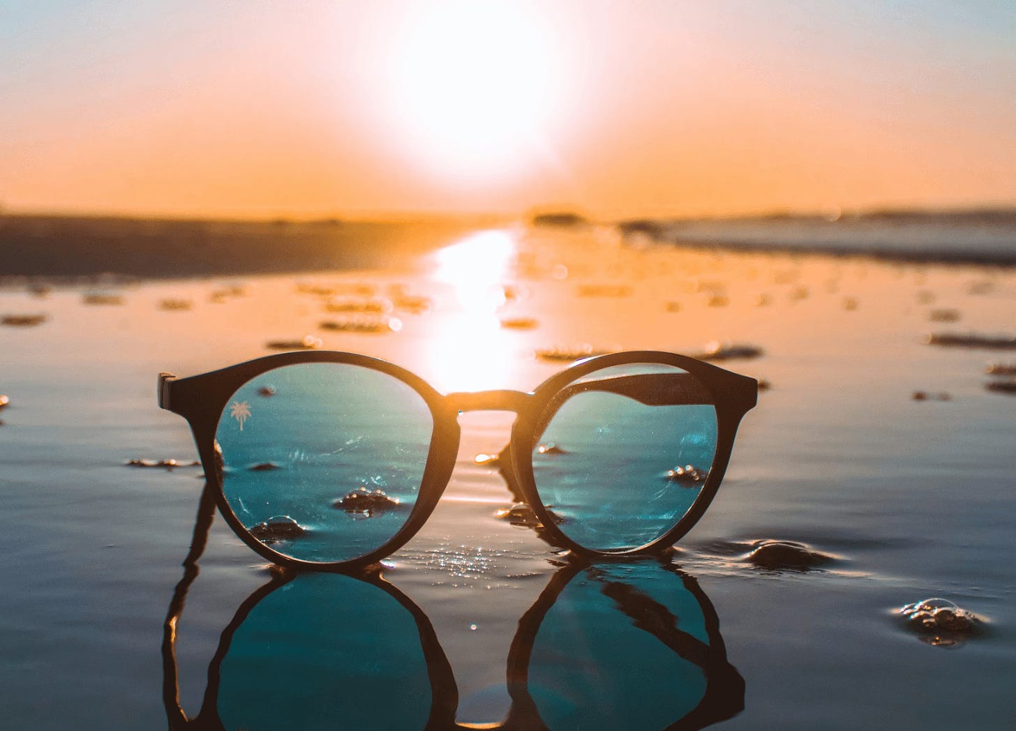 Sunglasses on beach sand at sunset
