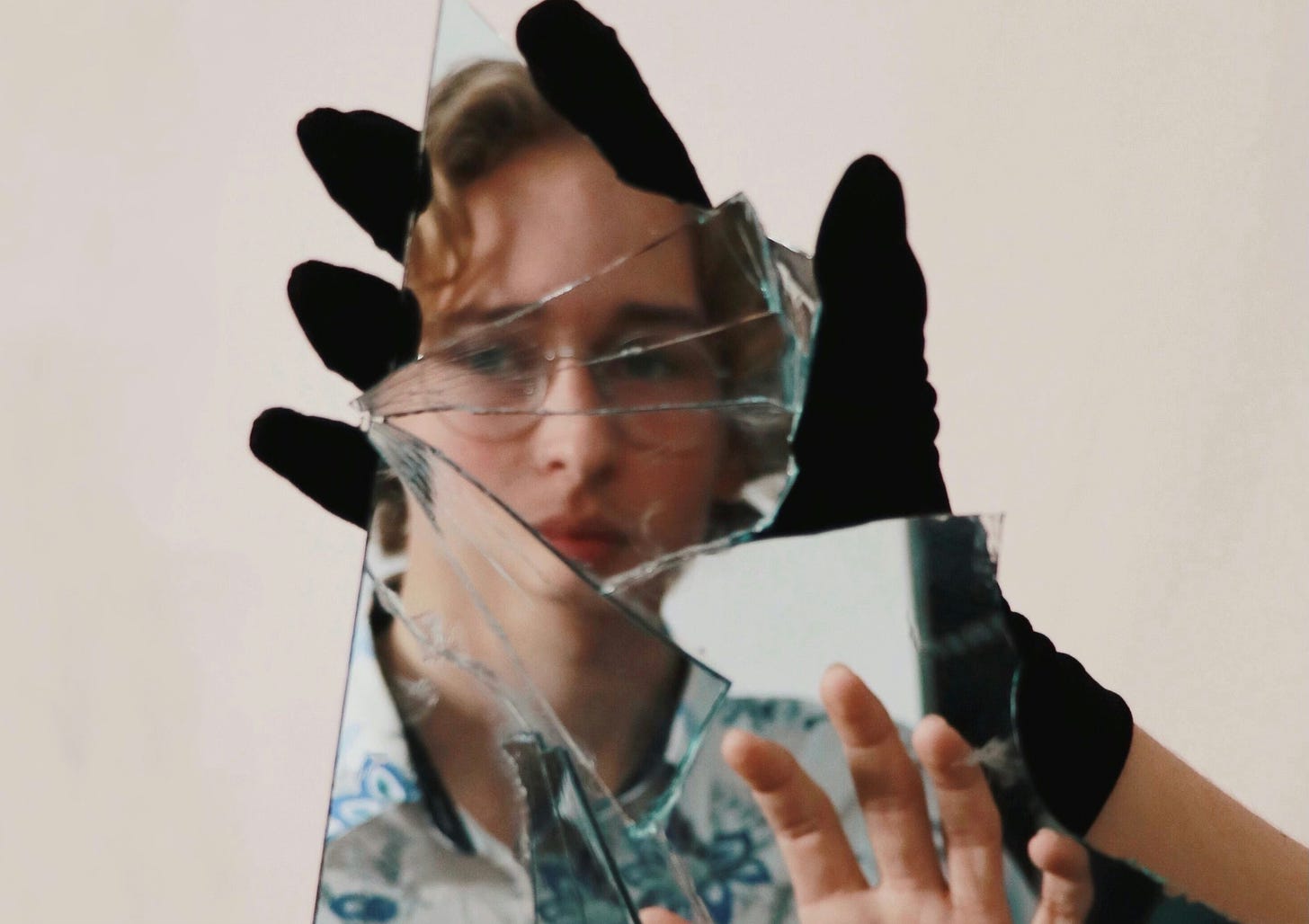 Woman with glasses looking at herself broken mirror