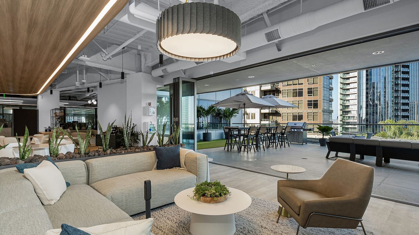 A living room-style segment of a new office space with views of downtown.