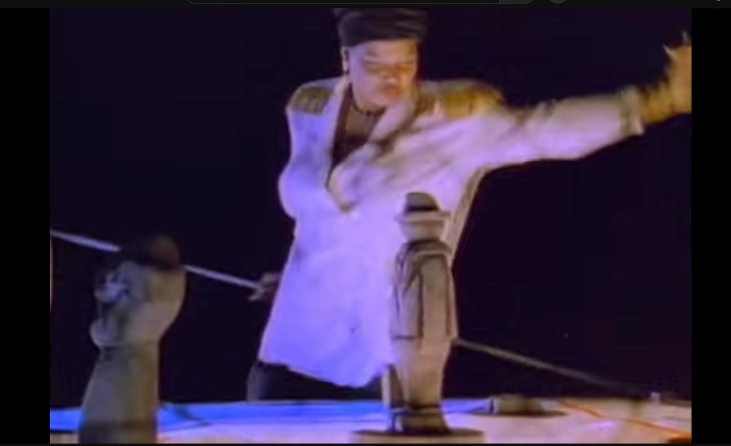 Still of "Ladies First" music video featuring Latifah knocking over giant chess pieces. 