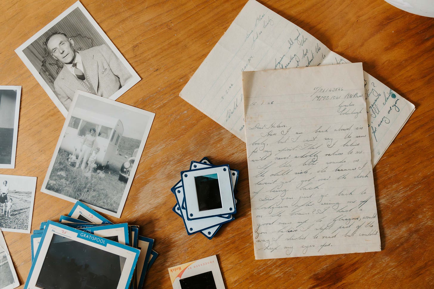 A wooden table with old photos, slides and letters on it