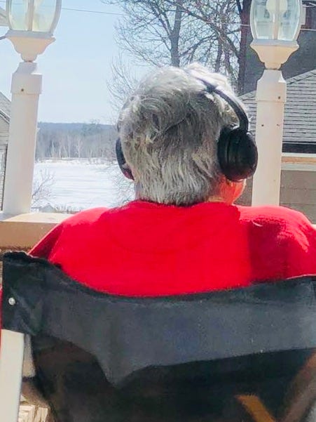 Jessica Waite's mom Bonnie Brady listening to an audiobook through noise-cancelling headphones while sitting outdoors.