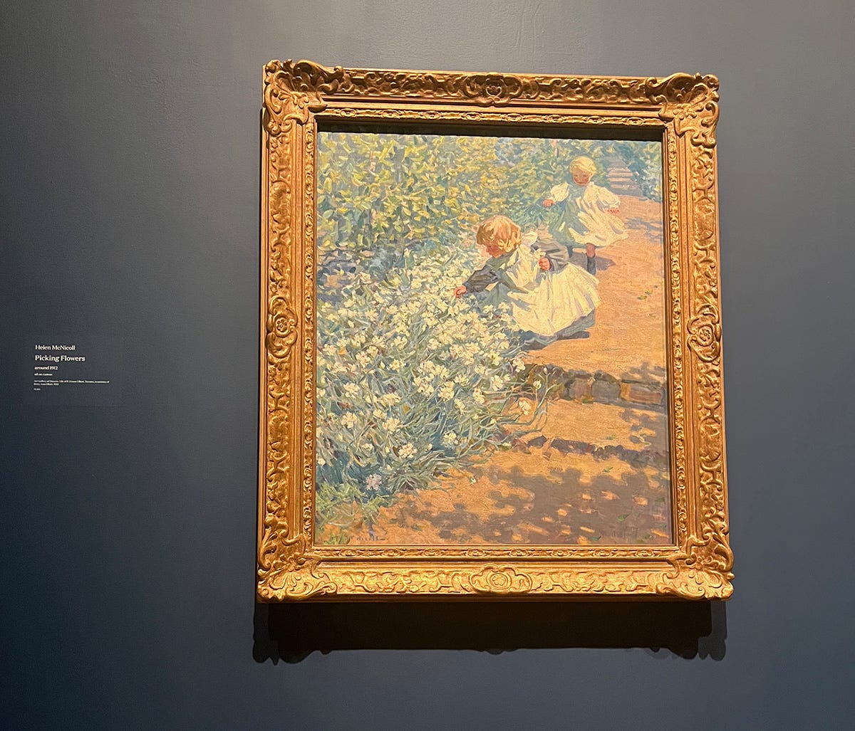 Framed painting of two young, blonde children by a bed of small white flowers along a red dirt pathway. The closer child wears a white apron over a light blue dress and bends to pick a flower from the bed. The child behind her wears a brilliant white dress that flares around her as she walks.