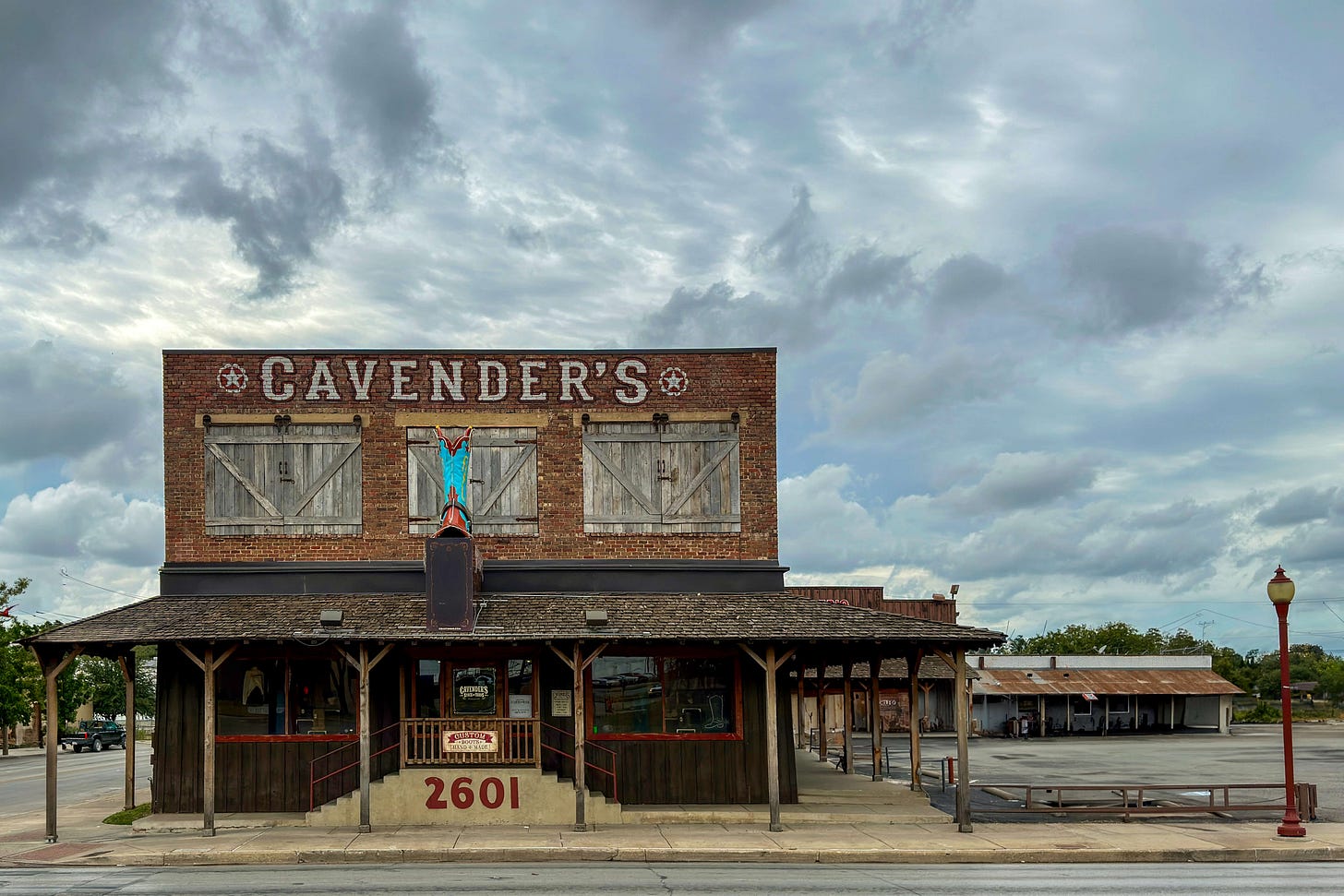 Brick facade of the historic western store at 2601 N Main Street in Fort Worth, Texas: The word “Cavender's” is emblazoned above the wooden porch, with an oversized cowboy boot in front as an advertisement. The two-story building with barn door shutters served as the traditional “Luskey's/Ryon's Western Store” until 2016. Brick facade of the historic western store at 2601 N Main Street in Fort Worth, Texas: The word “Cavender's” is emblazoned above the wooden porch, with an oversized cowboy boot in front as an advertisement. The two-story building with barn door shutters served as the traditional “Luskey's/Ryon's Western Store” until 2016.