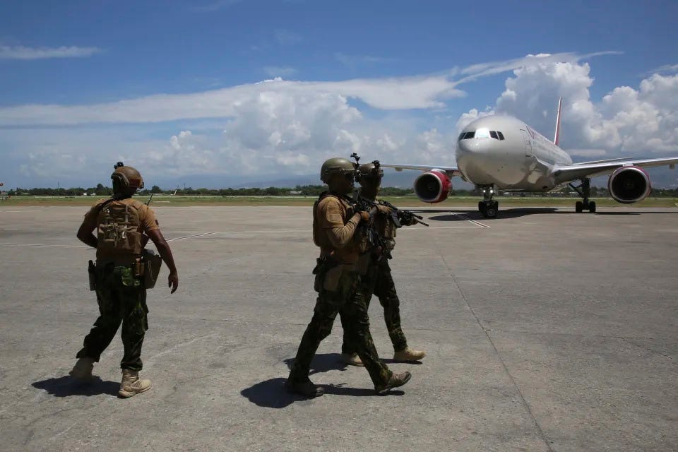 Kenyan police who are part of a UN-backed multinational force patrol the tarmac after a plane, behind, landed with more Kenyan police at Toussaint Louverture International Airport in Port-au-Prince, Haiti, Tuesday, July 16, 2024. Another 200 police officers from Kenya arrived for a U.N.-backed mission led by the East African country to battle violent gangs that have taken over parts of the Caribbean country. (AP Photo/Odelyn Joseph)