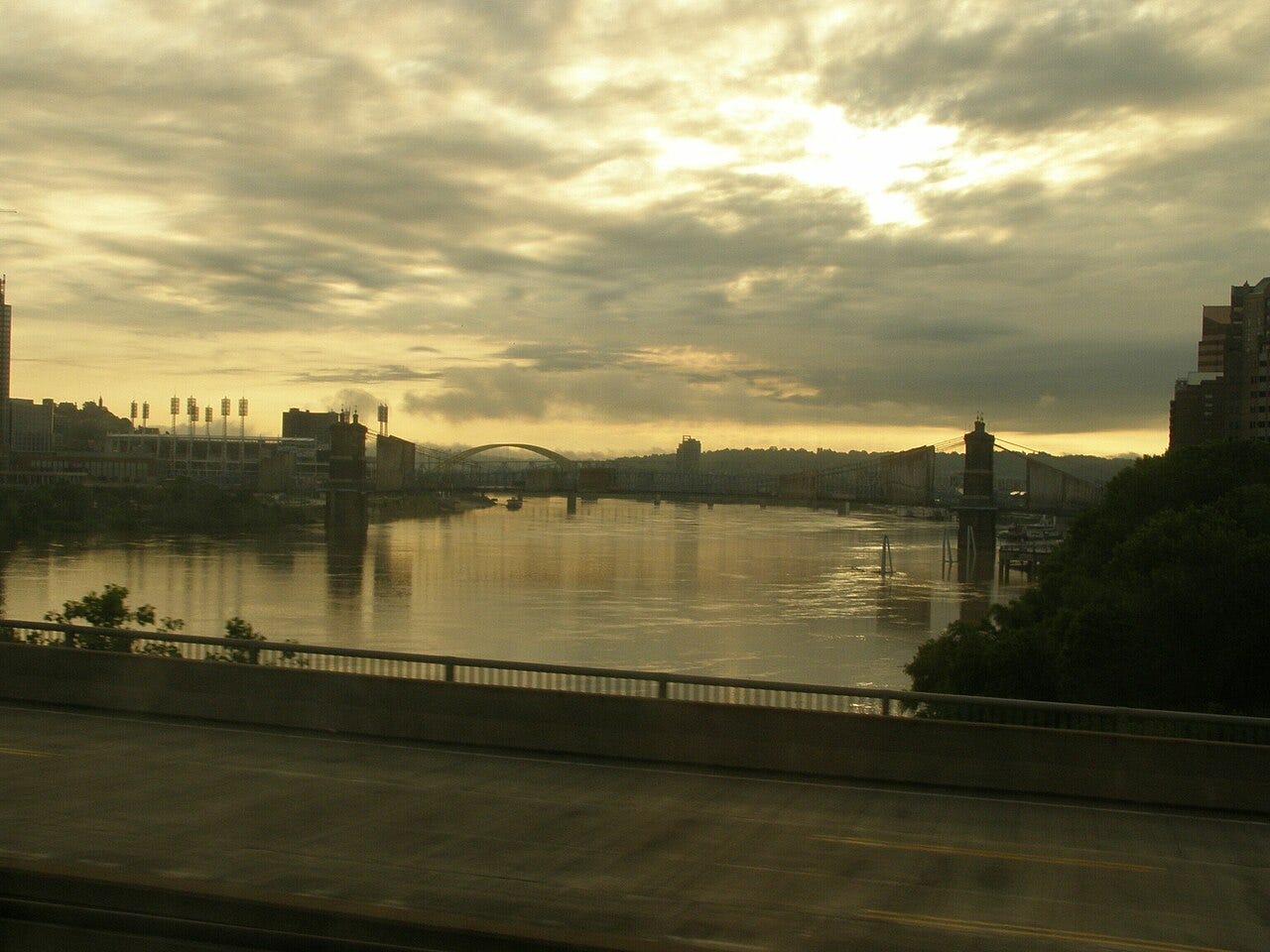 Color photo of Ohio River with view of two bridges in background from bridge in foreground