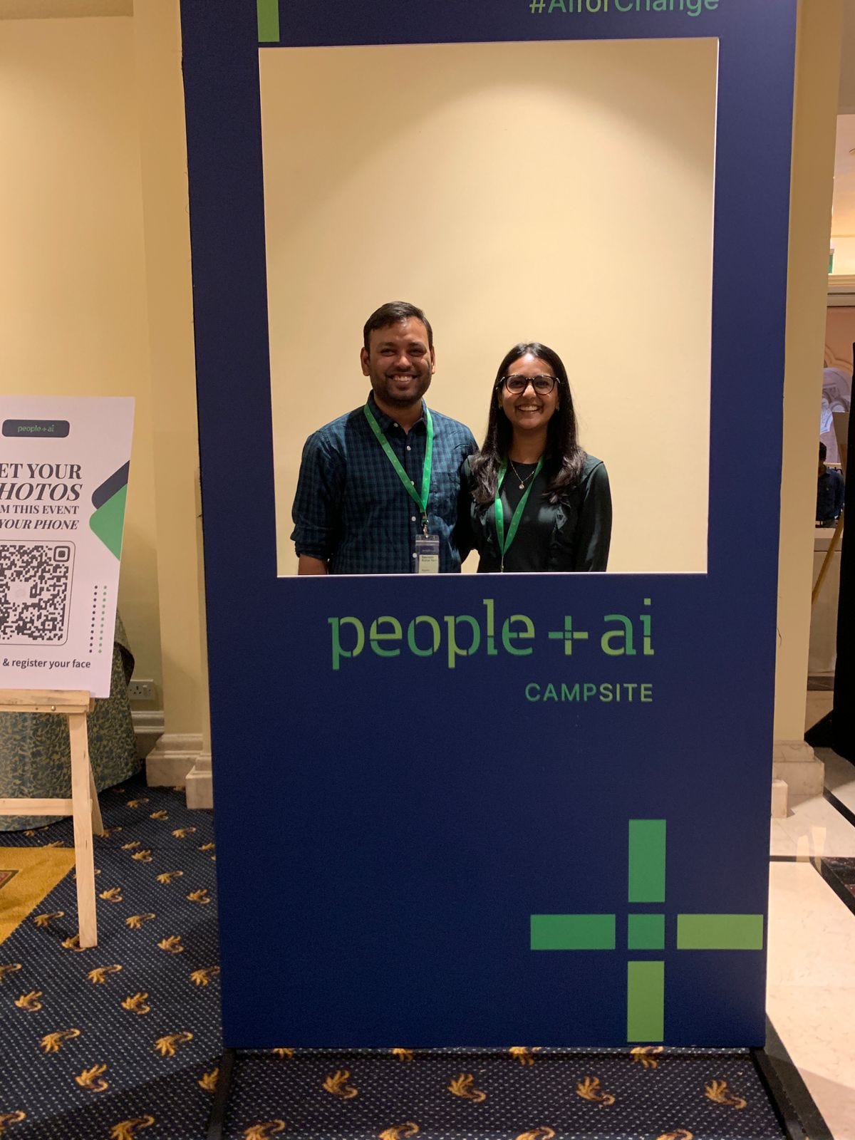 Saurabh standing with his colleague Smita in a photobooth that says "people + ai campsite"