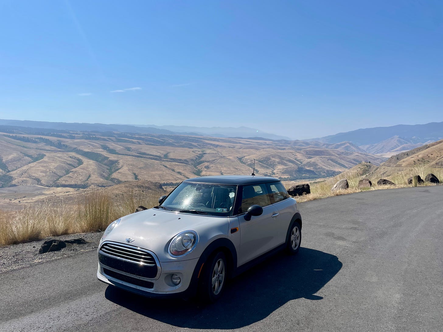 Photograph of a silver MINI Cooper against a backdrop of rolling desert hills.