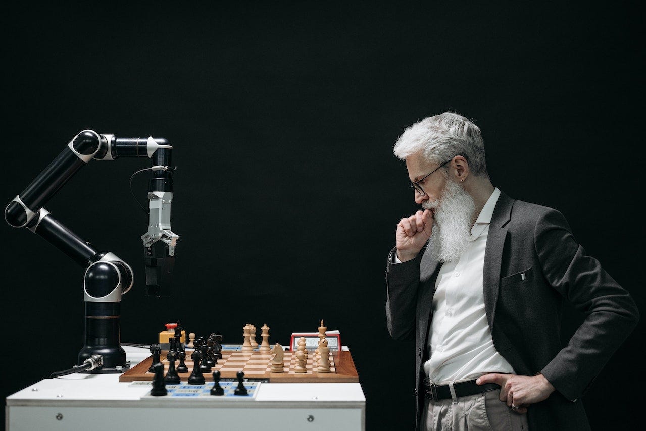 Man thinking of his next chess move while playing with a robot arm