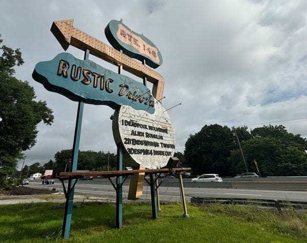 A blue road sign with a large yellow arrow sits beside a four lane highway