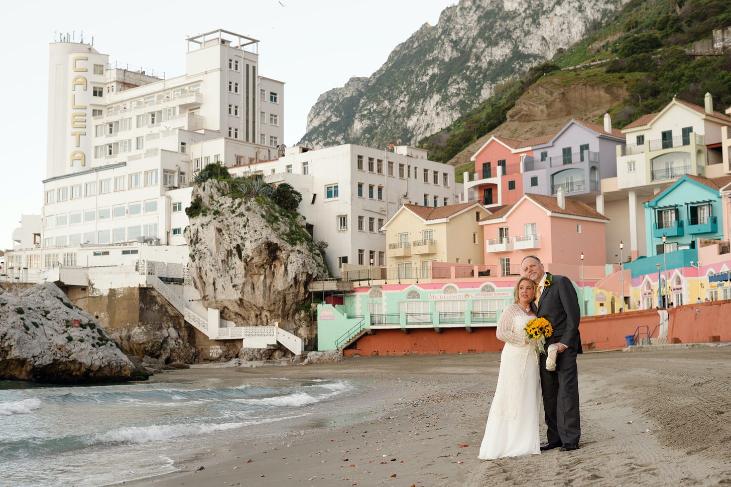 wide angle view of the beach and the Caleta Hotel in Gibraltar; my wife and I are standing in the front right foreground on our wedding day in 2013