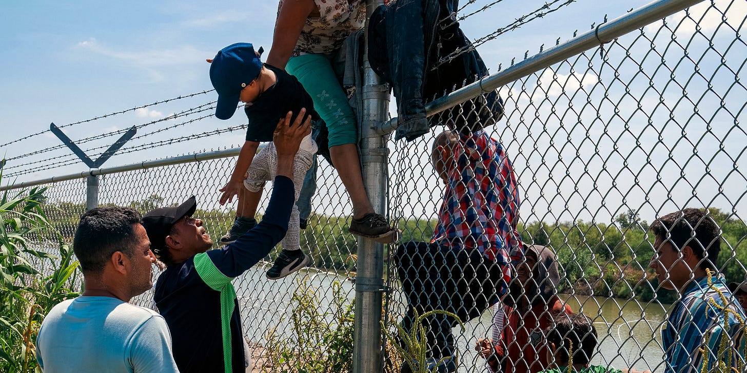 Migrants climb over a barbed wire fence after crossing the Rio Grande into US from Mexico, in Eagle Pass, Texas on August 25, 2023. (Photo by SUZANNE CORDEIRO / AFP) (Photo by SUZANNE CORDEIRO/AFP via Getty Images)