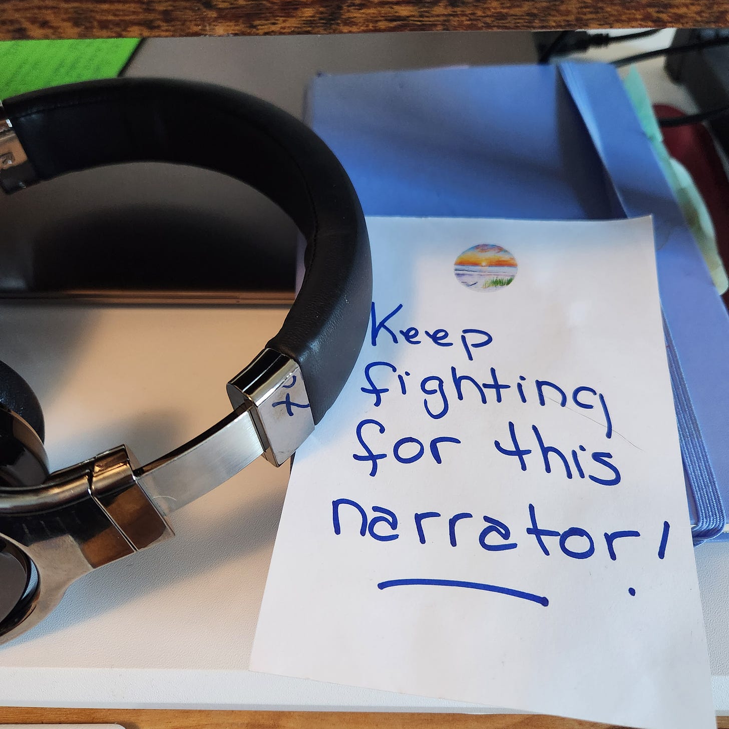 headphones on a laptop next to a note: keep fighting for this narrator