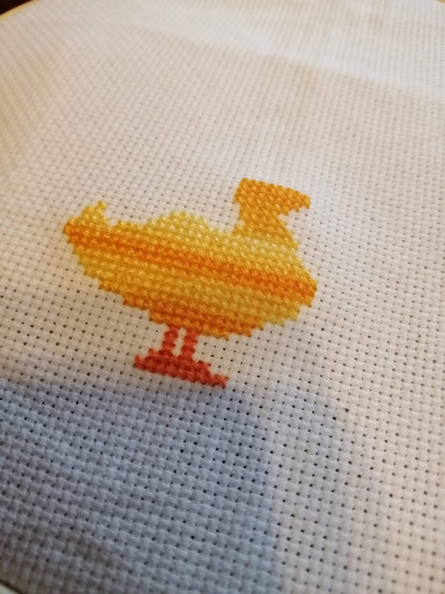 cross stitch in progress of the bottom part of a duck missing the top of its head. There is no text yet