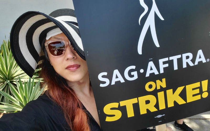 Nicky, in a black-and-white sunhat and sunglasses, holds a picket sign that reads “SAG-AFTRA on Strike!” while picketing at Sony’s Studios in Culver City in July.